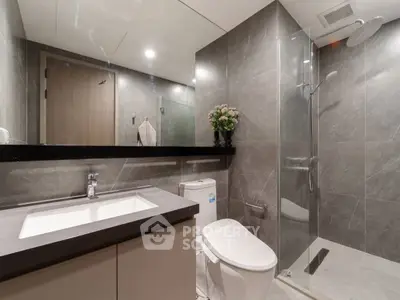 Modern bathroom with sleek design, featuring a glass shower and elegant fixtures.