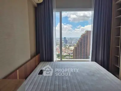 Spacious bedroom with stunning city view from large window, perfect for urban living.