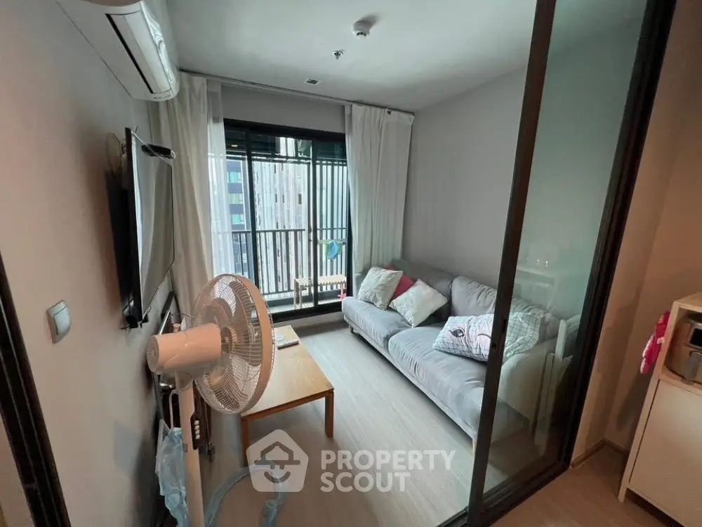 Cozy living room with modern decor and balcony view in urban apartment.