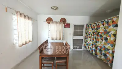 Spacious dining area with wooden table and colorful curtains, perfect for family gatherings.