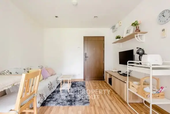 Cozy living room with modern decor and wooden flooring, featuring a TV and stylish furniture.