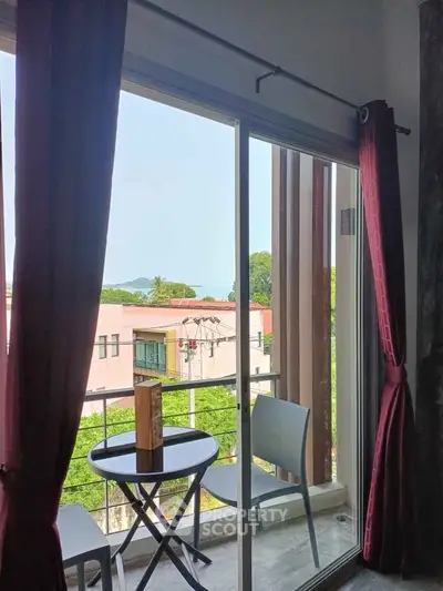 Charming balcony view with cozy seating overlooking lush greenery and distant hills, perfect for relaxation.
