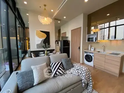 Modern living room with open kitchen, stylish decor, and large windows in urban apartment.