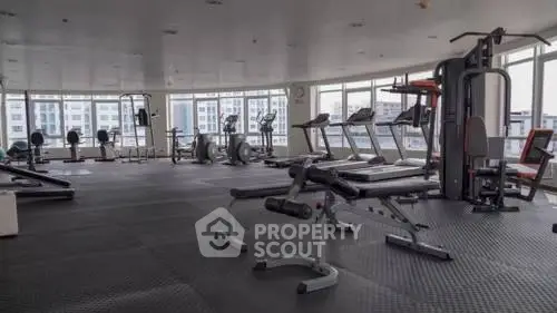 Spacious modern gym with panoramic city views and state-of-the-art fitness equipment.