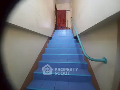 Charming stairway with blue tiles leading to a vibrant red door, perfect for unique home entry.