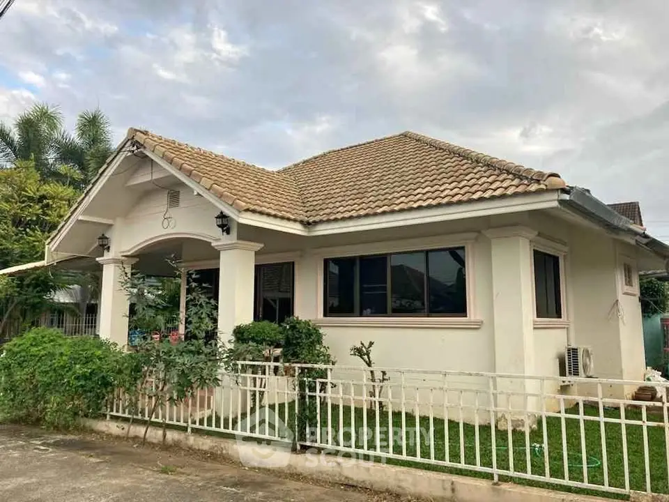 Charming single-story house with tiled roof and lush garden in serene neighborhood.