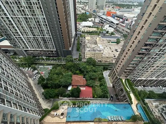 Stunning aerial view of modern high-rise buildings with a luxurious pool and lush greenery in an urban setting.
