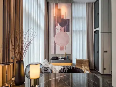 Modern living room with high ceilings and abstract art, featuring elegant decor and natural light.