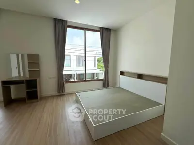 Spacious bedroom with large window and modern furniture in a bright, airy setting.