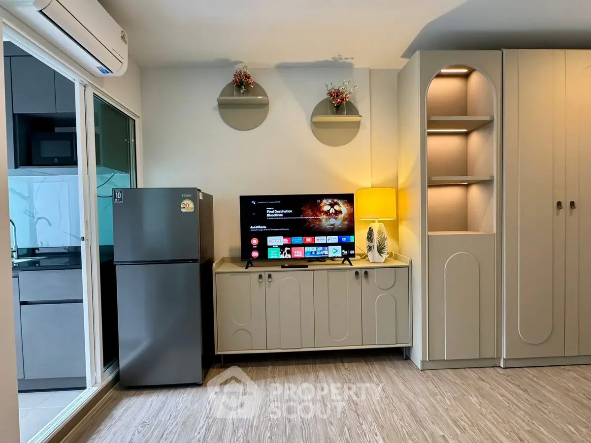 Modern living room with stylish cabinetry and smart TV, adjacent to a sleek kitchen area.