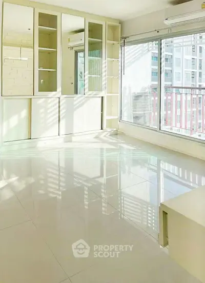 Bright and spacious living room with large windows and built-in storage in modern apartment.