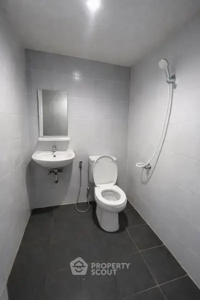 Modern minimalist bathroom with sleek fixtures and tiled walls.