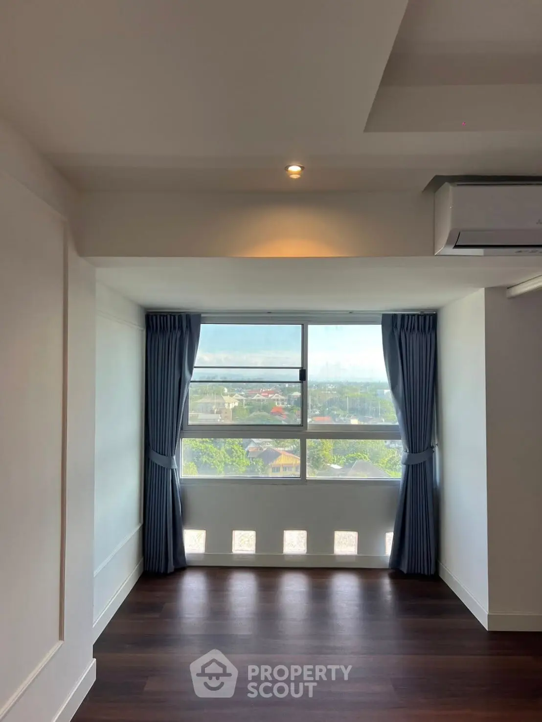 Bright room with large window and blue curtains offering a scenic view.