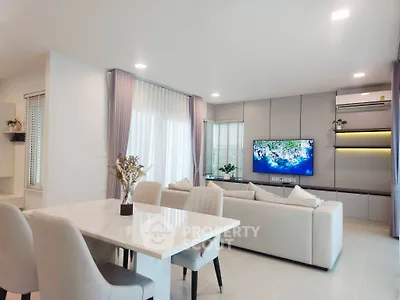 Modern living room with elegant decor and large TV, featuring a stylish dining area and cozy seating.