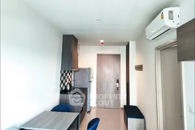 Modern compact kitchen with dining area and air conditioning in a cozy apartment.