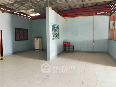 Spacious open-plan room with tiled flooring and minimal furnishings, ideal for customization.