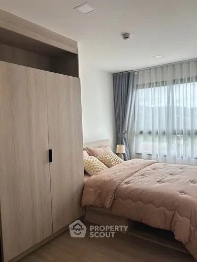 Cozy bedroom with large window and modern wardrobe, perfect for relaxation and comfort.