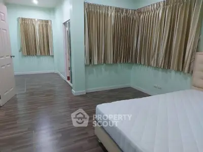 Spacious bedroom with elegant curtains and hardwood flooring