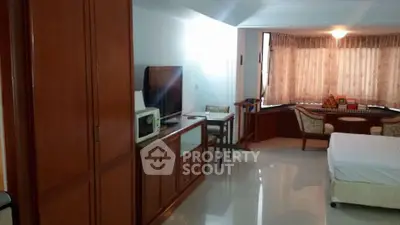 Spacious studio apartment with cozy seating area and large windows.