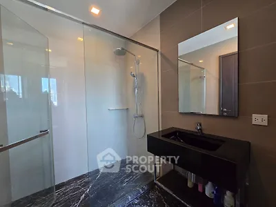 Modern bathroom with sleek black sink and spacious glass shower enclosure.