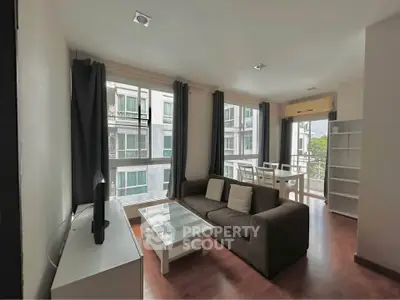 Spacious living room with modern furniture and large windows offering natural light and city views.