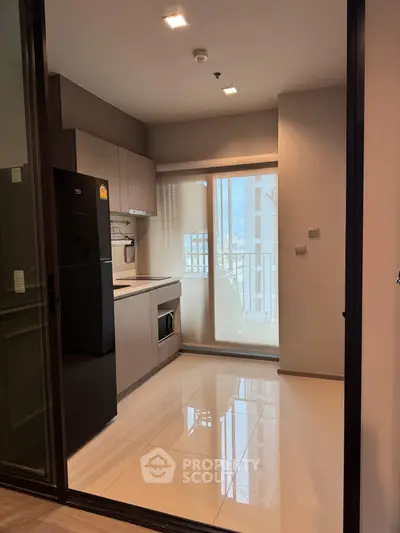 Modern kitchen with sleek cabinetry and appliances, featuring a large window with a view.