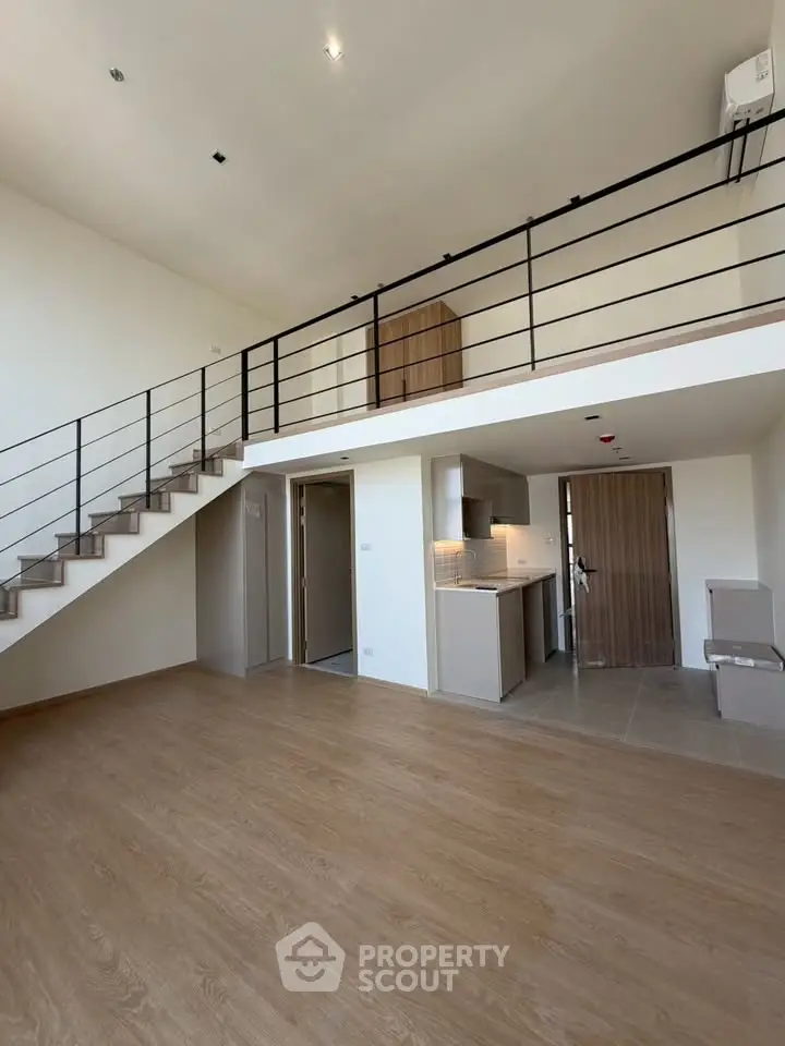 Spacious modern loft with open kitchen and mezzanine, featuring sleek wooden flooring and contemporary design.