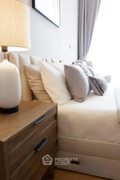 Elegant bedroom with plush bedding and stylish bedside lamp in modern apartment.