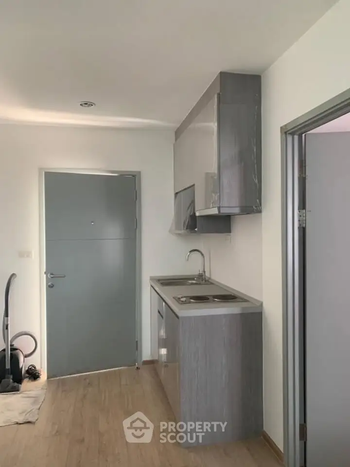 Modern compact kitchen with sleek cabinetry and integrated appliances in a minimalist apartment.