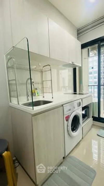 Modern kitchen with washing machine and sleek cabinetry in a compact apartment setting.