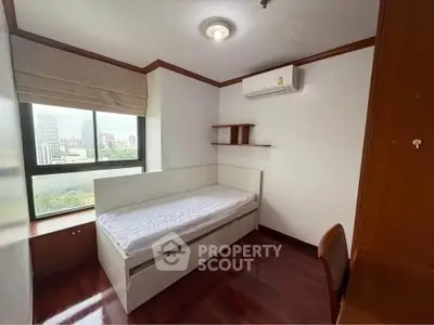 Cozy bedroom with city view, featuring wooden floors and air conditioning, perfect for urban living.