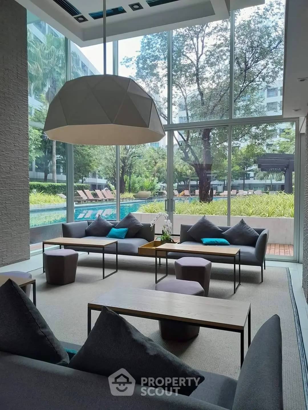 Luxurious living room with floor-to-ceiling windows overlooking a serene pool and garden.