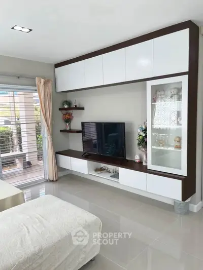 Modern living room with sleek TV unit and large window for natural light.