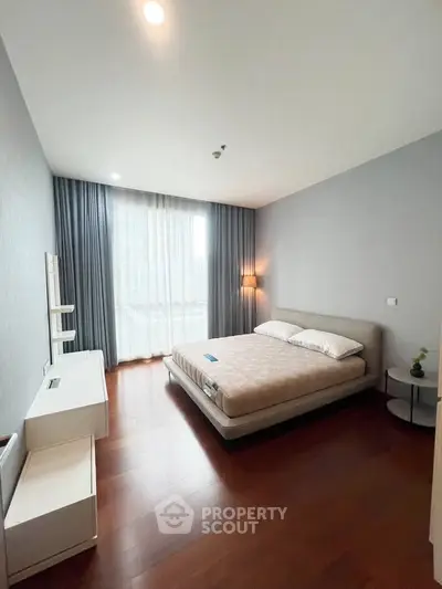 Spacious bedroom with modern decor and large window offering natural light.