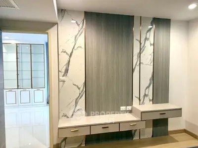 Modern interior with elegant marble accent wall and built-in storage in a stylish living space.