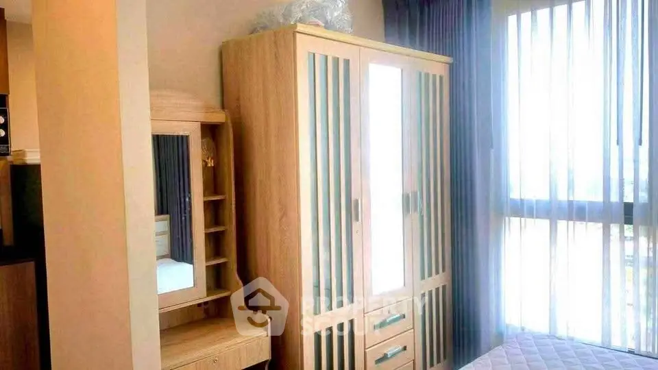 Bright bedroom with modern wardrobe and vanity near large window with sheer curtains.