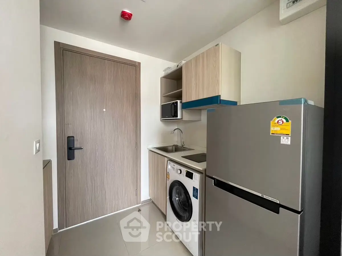 Compact modern kitchen with washing machine and fridge in a stylish apartment.