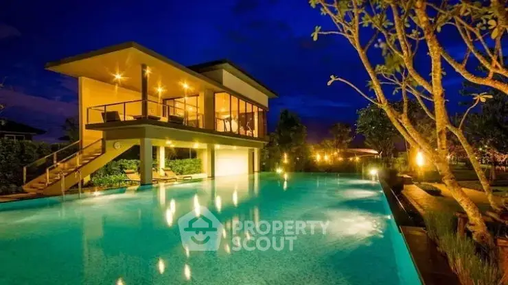 Luxurious modern villa with stunning illuminated pool and lush garden at night.
