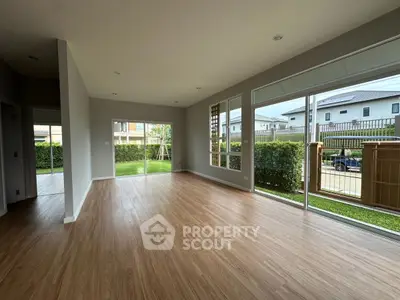 Spacious empty living room with large windows and wooden flooring in modern home