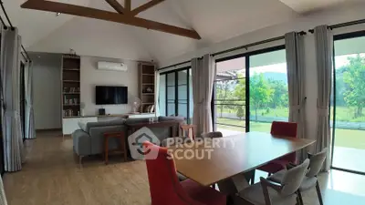 Spacious living room with modern decor and large windows overlooking greenery.
