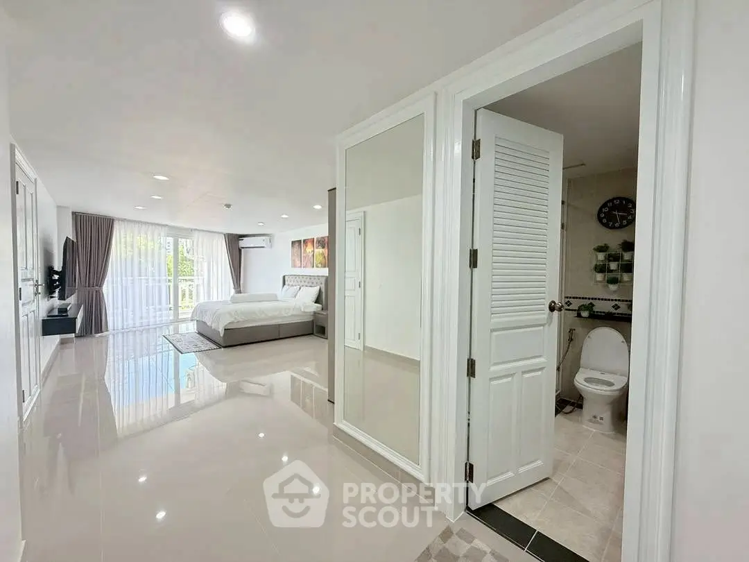 Spacious modern bedroom with ensuite bathroom and large windows for natural light.
