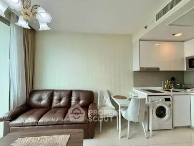 Modern living room with leather sofa and compact kitchen featuring washing machine.