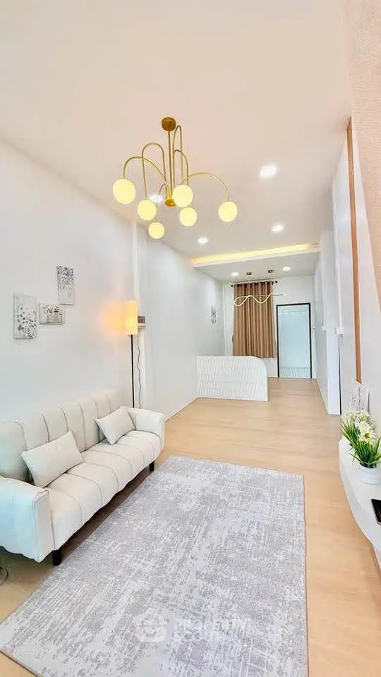 Elegant living room with modern chandelier and cozy sofa in a bright, spacious apartment.