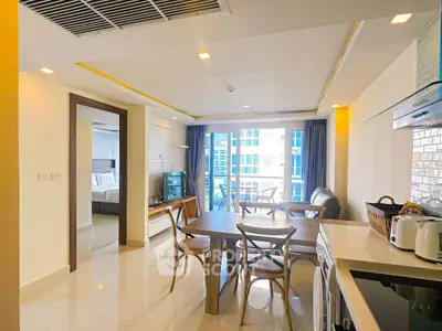 Modern open-plan living room with dining area and kitchen, featuring sleek furniture and bright natural light.