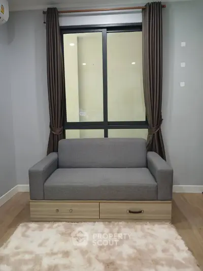 Modern living room with stylish gray sofa and large window, perfect for cozy relaxation.