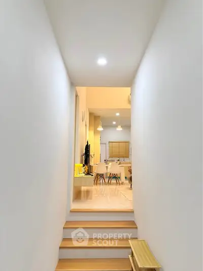 Modern interior hallway leading to a stylish open-plan kitchen and dining area with warm lighting.