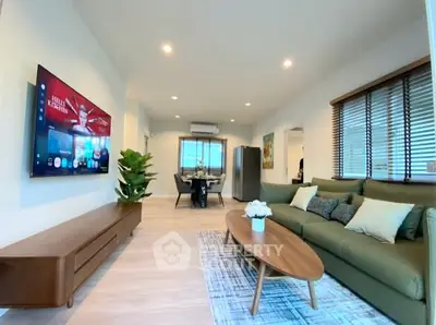 Modern living room with stylish furniture and open layout, featuring a large TV and dining area.
