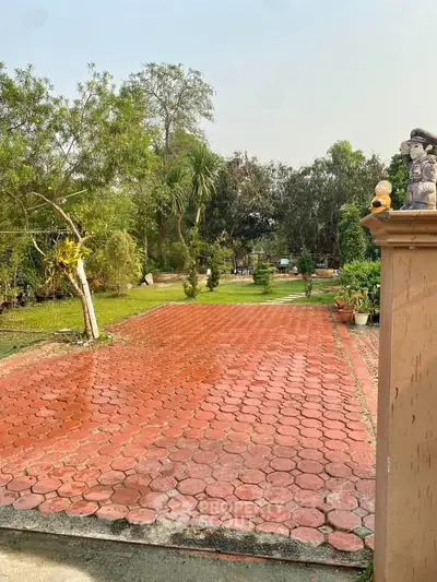 Spacious garden with red brick pathway and lush greenery, perfect for outdoor activities.