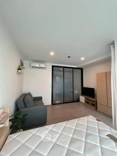 Modern studio apartment with sleek design and cozy furnishings, featuring a comfortable sofa and ample storage.