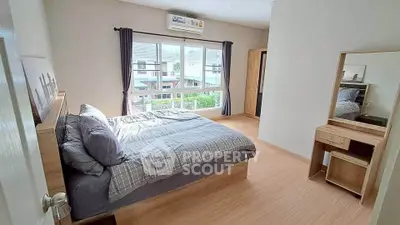 Spacious bedroom with large window and modern furnishings in a bright home.